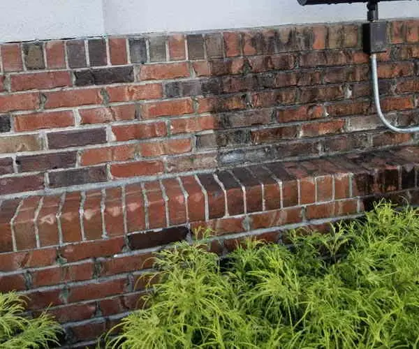 Brick wall with a cleaned section beside darker brick (Oct 2018)