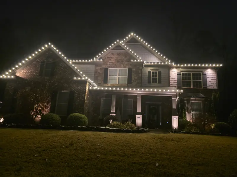 Warm-white roofline holiday lights after installation, Brookstone Country Club, Acworth, photographed at night on November 25, 2025.