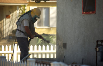 worker sandblasting a residential home